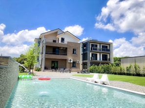 Un edificio moderno con piscina, asientos al aire libre y cielo despejado.