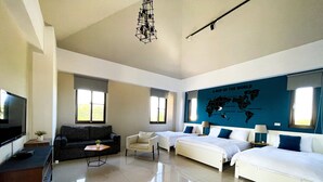 Una habitación de hotel moderna con televisión de pantalla plana, un sofá, una silla, dos camas, un escritorio y un mapa del mundo en la pared.