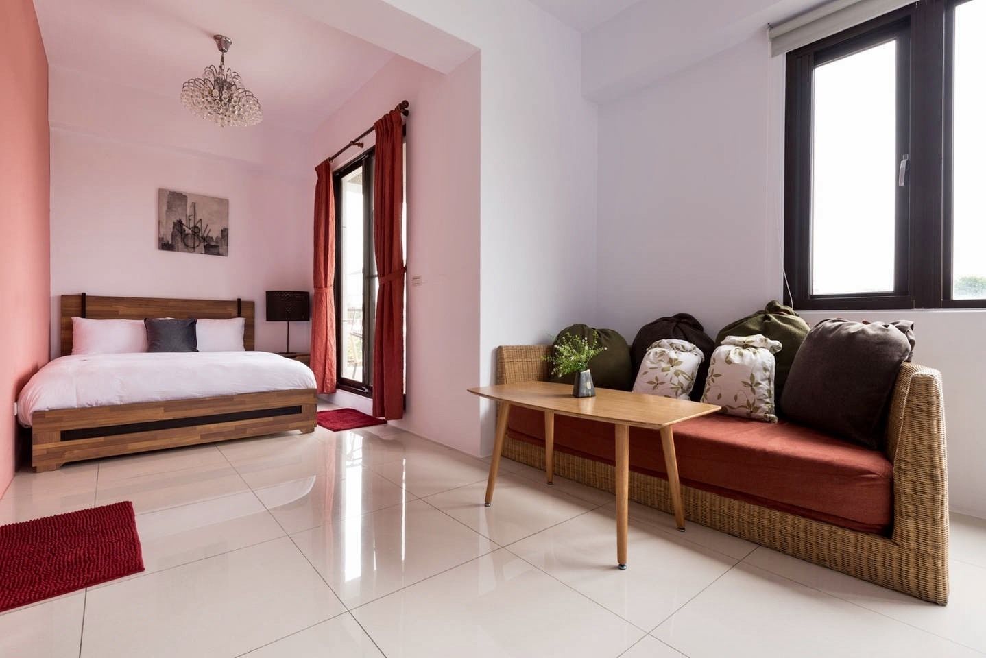 Une chambre à coucher avec un lit, une table de chevet, un tapis rouge, une fenêtre avec des rideaux et une vue sur l’extérieur.