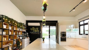 Una cocina moderna con una isla central, electrodomésticos integrados y una estantería negra decorada con objetos.