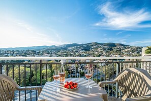 A balcony with a table set for two, two glasses of wine, and a plate of strawberries. - SAS Appart Hotel Mandelieu (Mandelieu la Napoule)