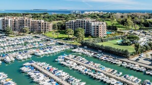A marina with numerous boats docked, surrounded by residential buildings and greenery. - SAS Appart Hotel Mandelieu (Mandelieu la Napoule)