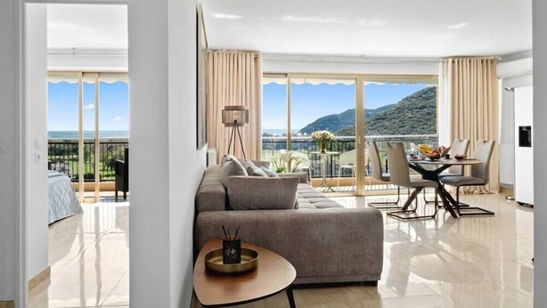 A modern hotel room with a balcony, a dining area, and a sofa. - SAS Appart Hotel Mandelieu (Mandelieu la Napoule)
