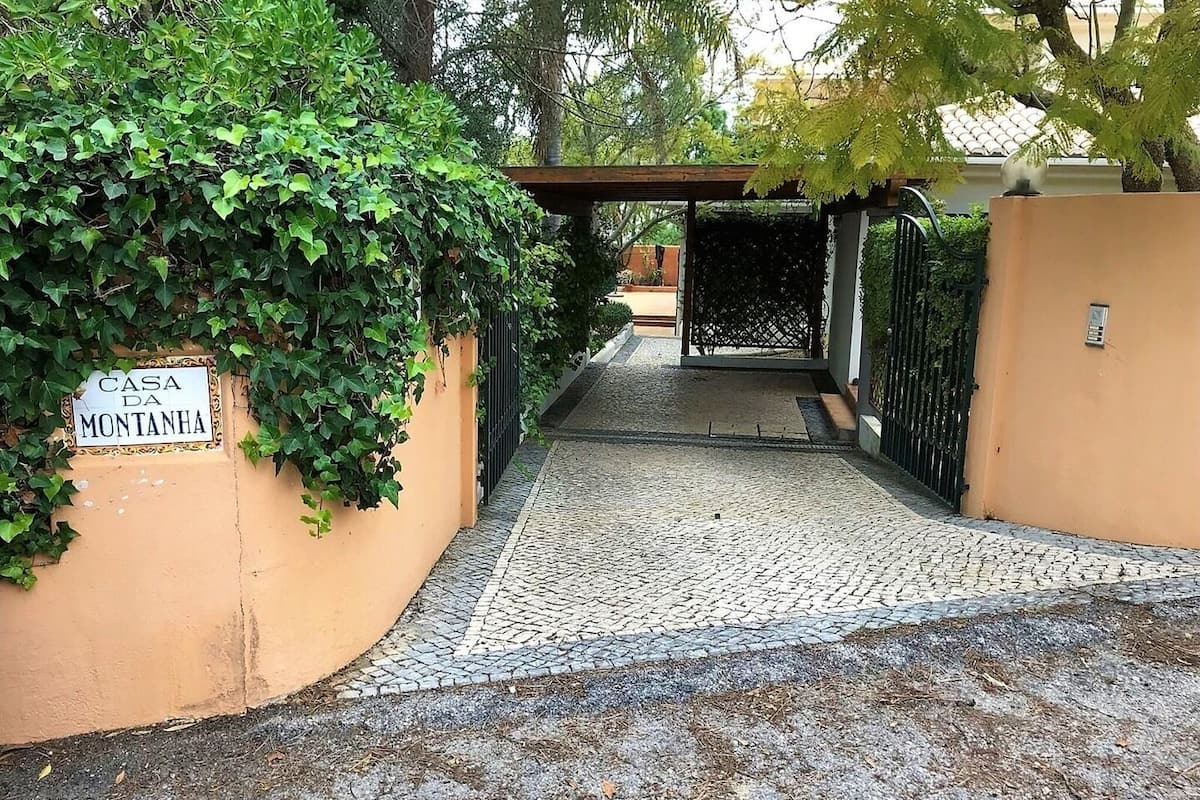 A paved pathway leading to a gated entrance with a sign reading "Casa da Montanha".