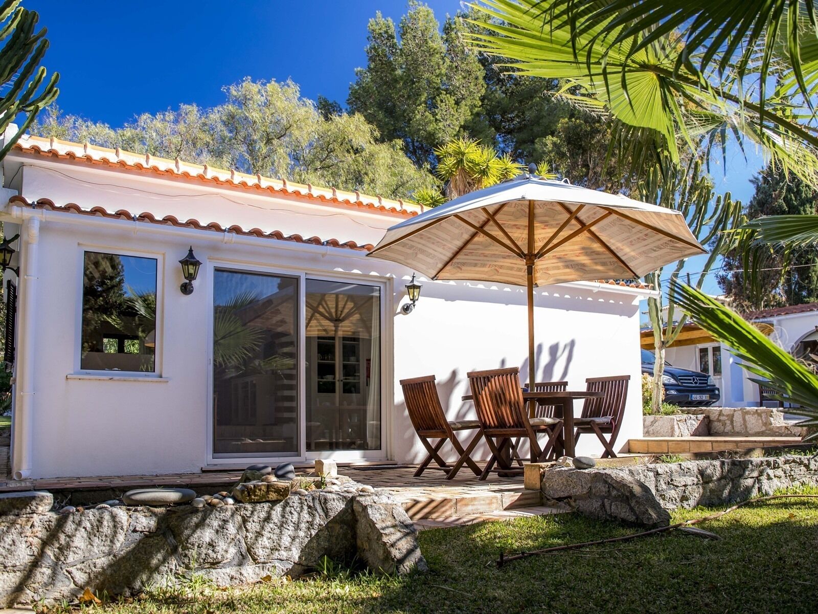 A small house with a patio, outdoor seating, and a large umbrella.