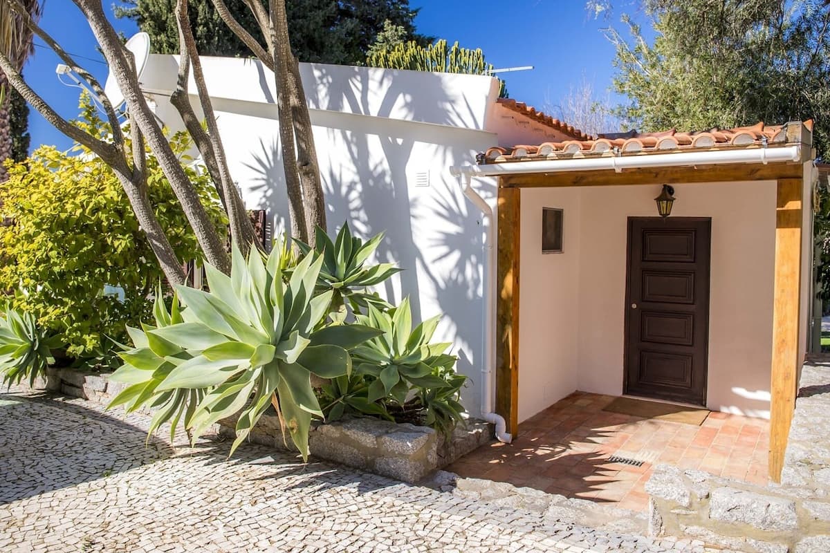 A small, enclosed outdoor area with a tiled roof, a door, and a white wall.