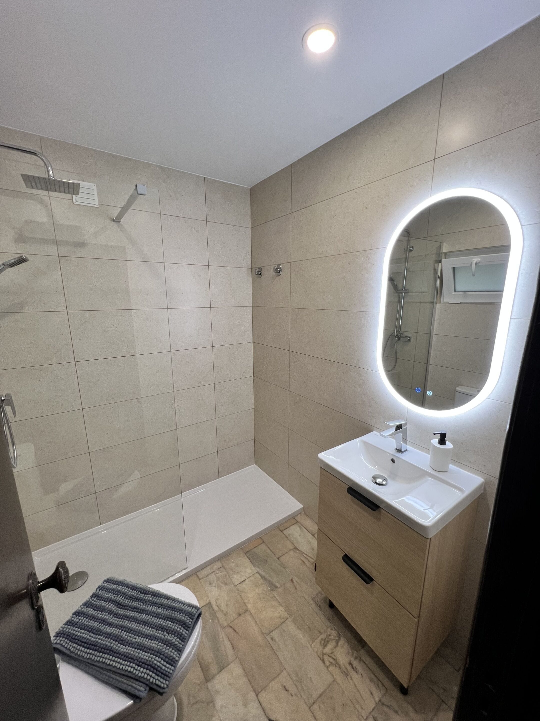 Un baño moderno con ducha, lavamanos con espejo e inodoro.
