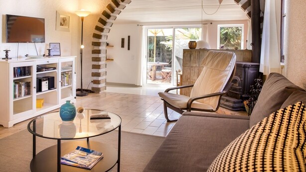 A spacious living room with a high ceiling, a built-in fireplace, a comfortable sofa, a glass coffee table, and a television. - Casa da Montanha (Lagos)