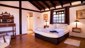 A bedroom with a large bed, wooden furniture, and a window with a view. - Casa da Montanha (Lagos)