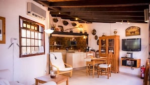 A cozy living room with a fireplace, a dining area, and a kitchen visible through an open door. - Casa da Montanha (Lagos)