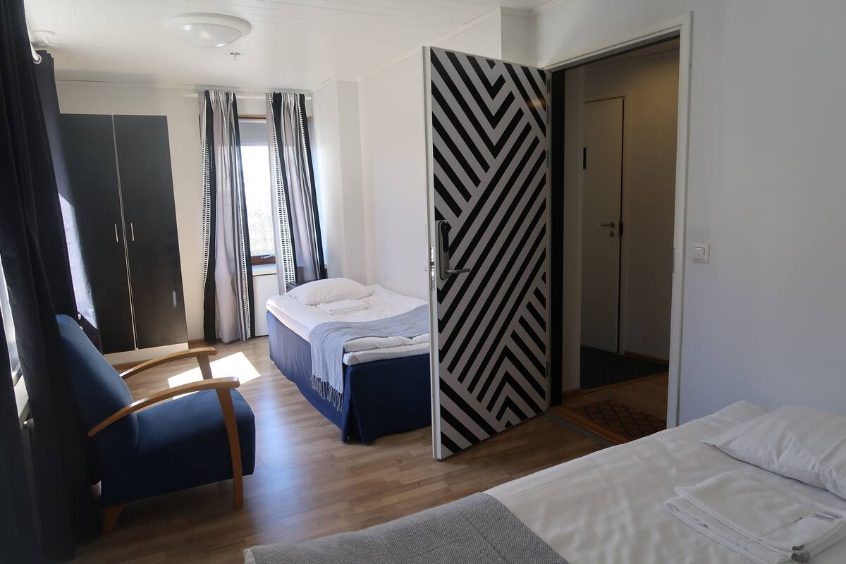 Un dormitorio con cama, una silla, un armario y una puerta con diseño en zigzag.
