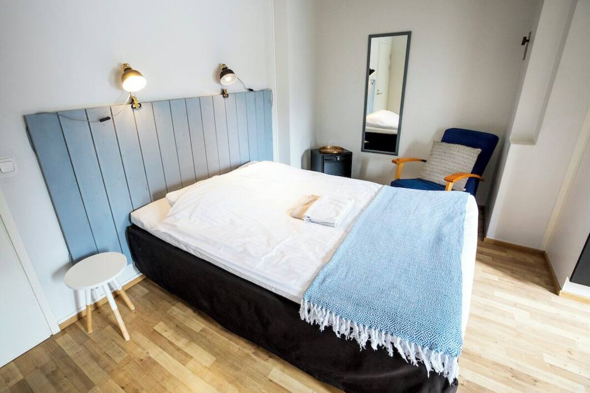 Un dormitorio con cama, lámparas de noche, una silla, una mesita y un espejo.