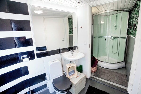 Un baño con inodoro, lavamanos y ducha con mampara de vidrio.
