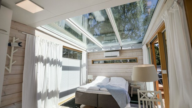 A modern bedroom with a skylight, a bed, a bedside table, and a chair. - Hostel Villa Kemi (Kemi)