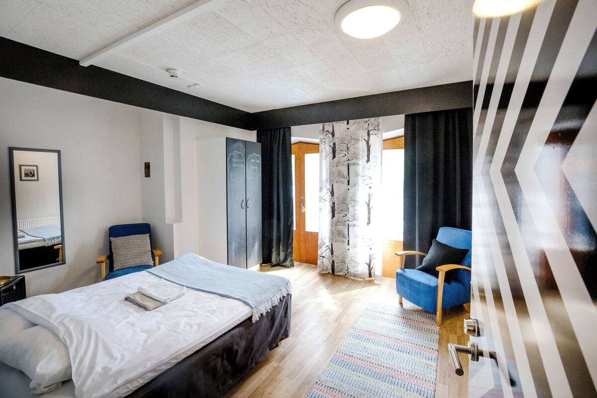 Habitación de hotel moderna con una cama grande, una silla, un armario y vistas al exterior.