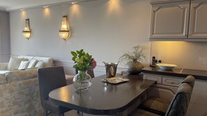 A modern kitchen with a dining area, featuring a round table, chairs, a vase with flowers, and a large pot on the counter. - Ferienhaus Weetstich (Sylt)