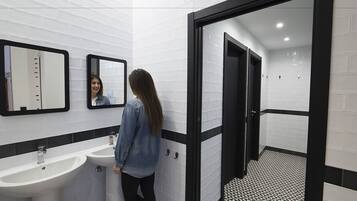 Une salle de bain avec deux lavabos, un miroir et une porte à cadre noir donnant sur une autre pièce.