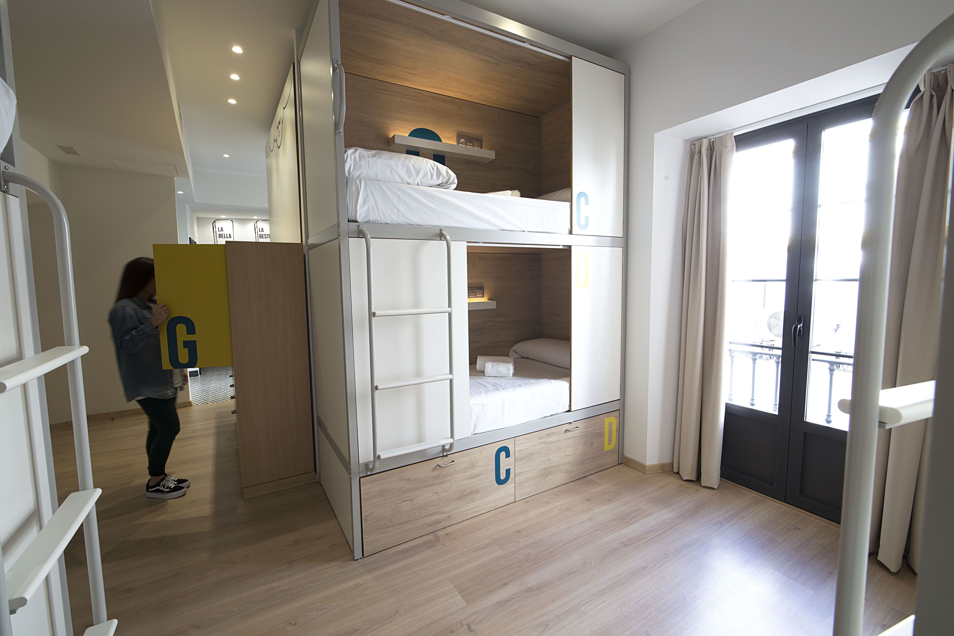 A bunk bed room with a wooden floor, a sliding door, and a view of the outside.