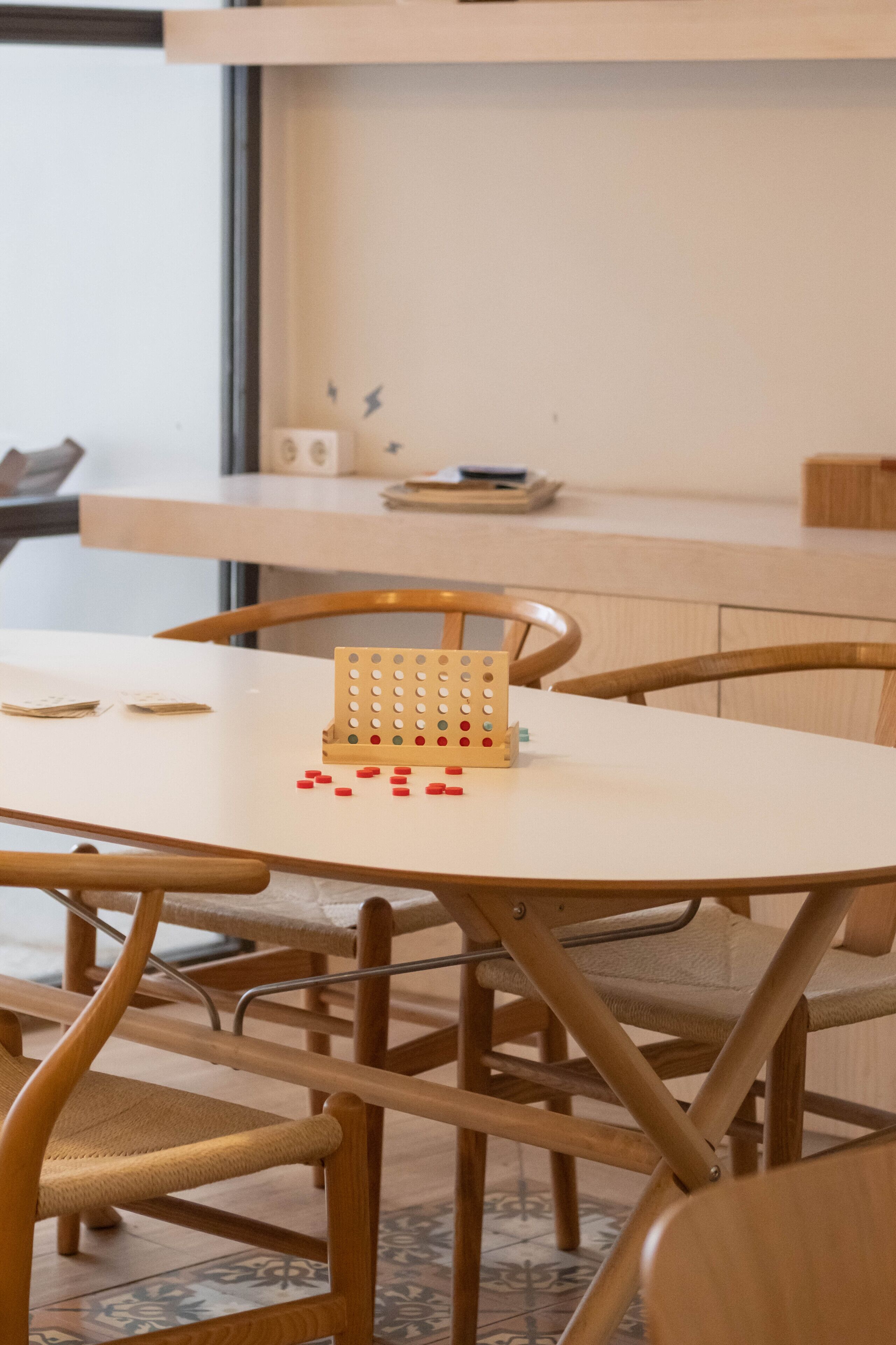 A dining table with a pegboard game, wooden chairs, and a white tablecloth.