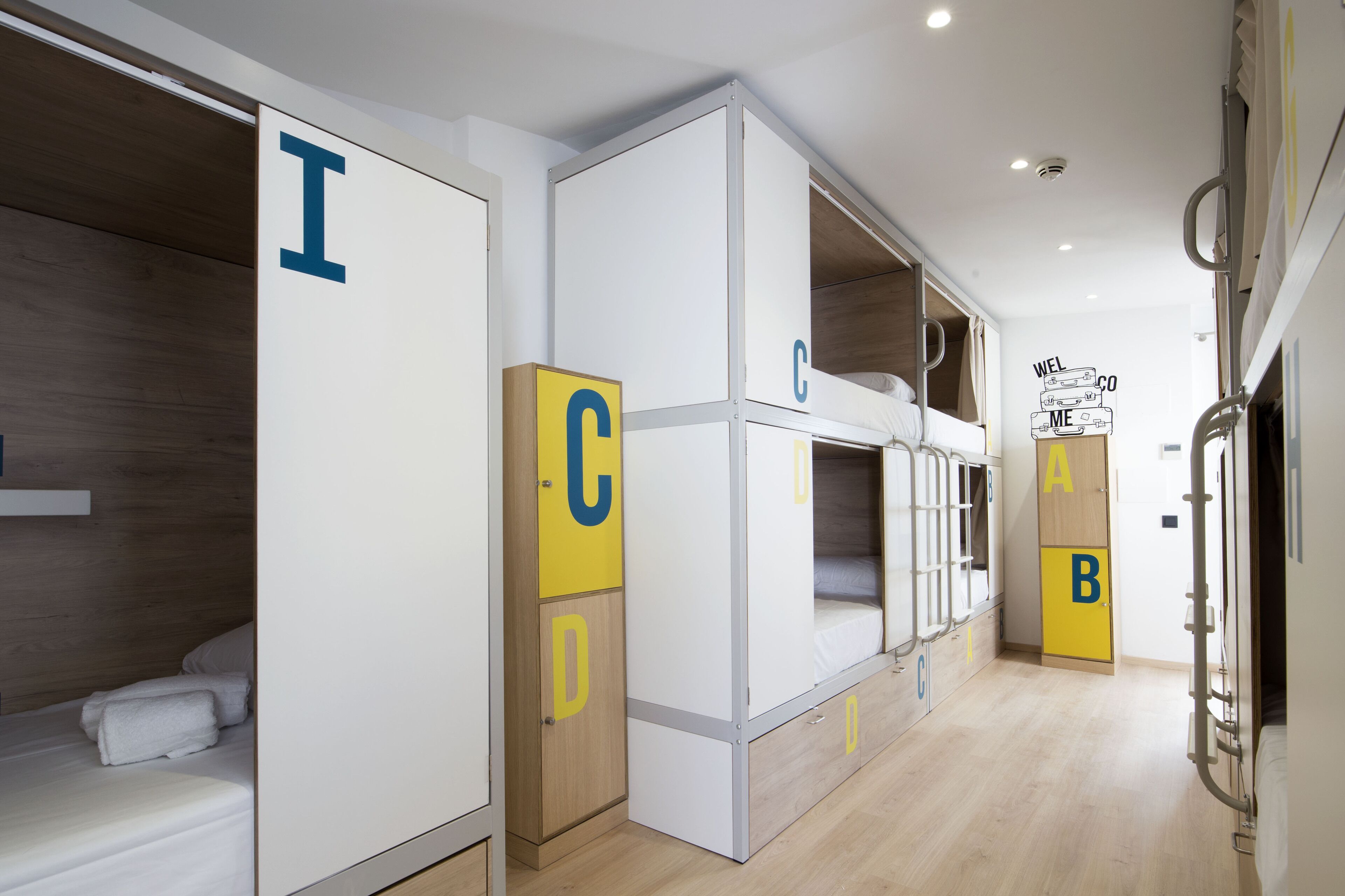 A modern hotel room with bunk beds, each labeled with a letter.