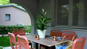 An outdoor patio with a table, chairs, a potted plant, and a basket.