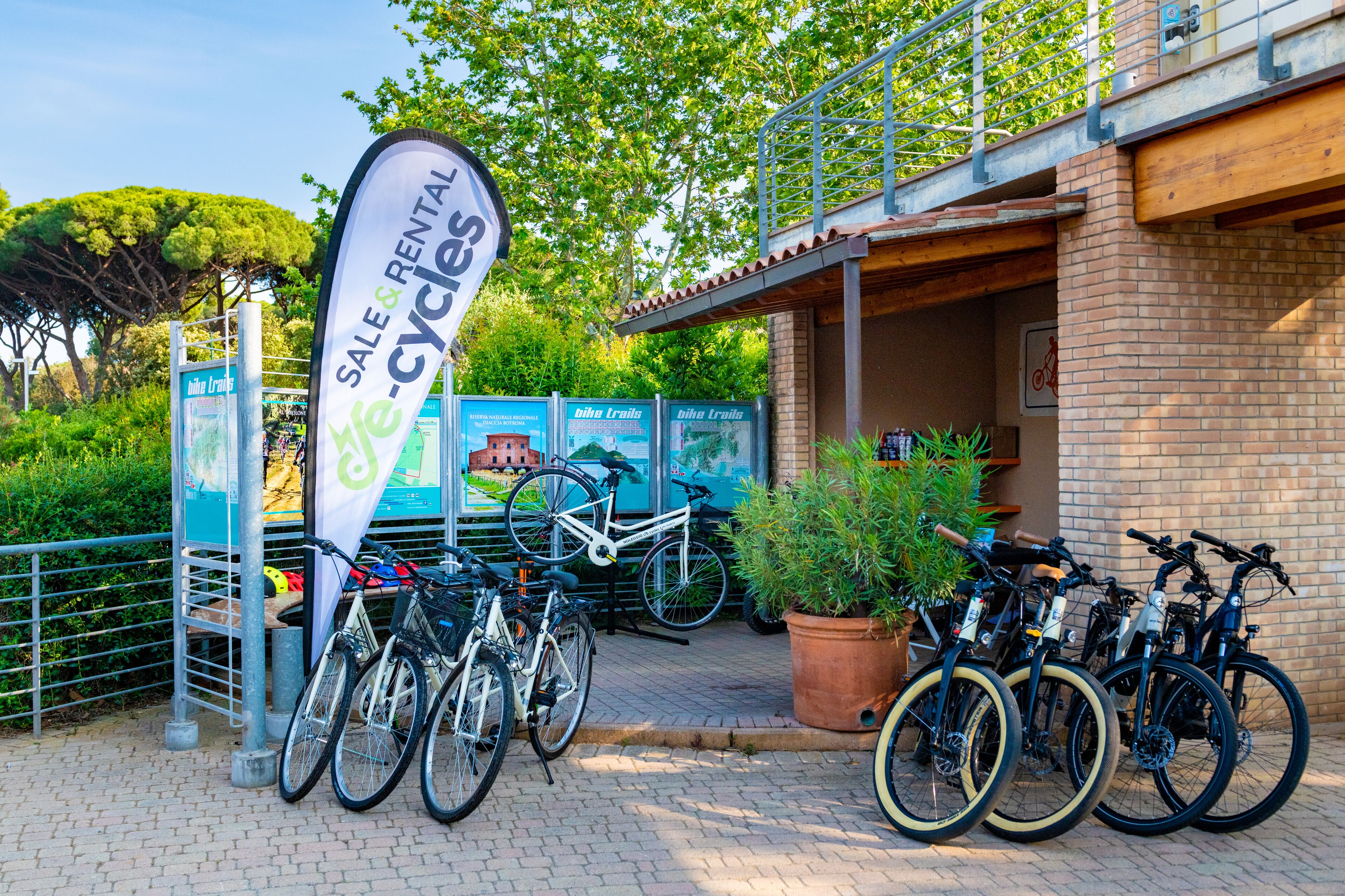 A bike rental station with several bicycles parked and a sign advertising sale and rental services.