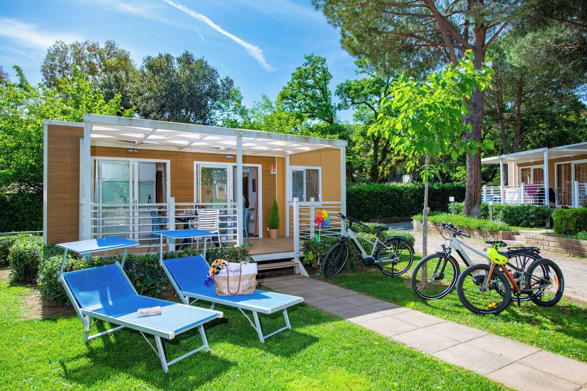 Un petit bâtiment d’un seul étage, doté d’un patio couvert, d’un espace extérieur aménagé pour s’asseoir et de quelques vélos garés à proximité.