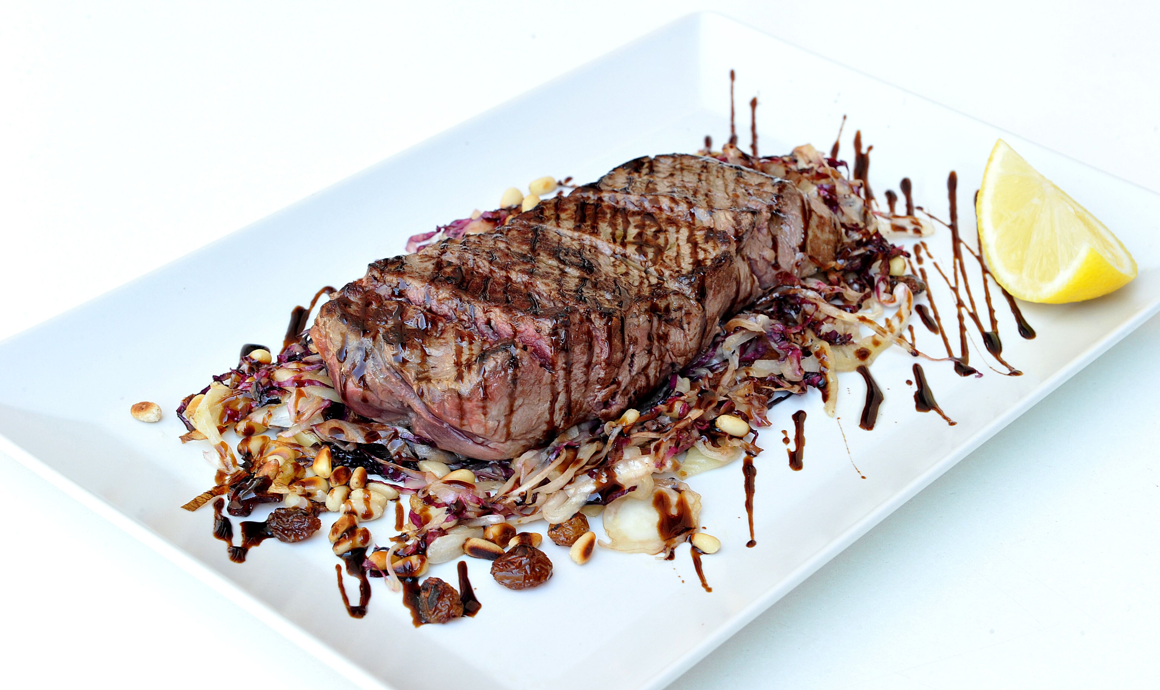 Ein Steak mit Gemüse und Soße auf einem weißen Teller.