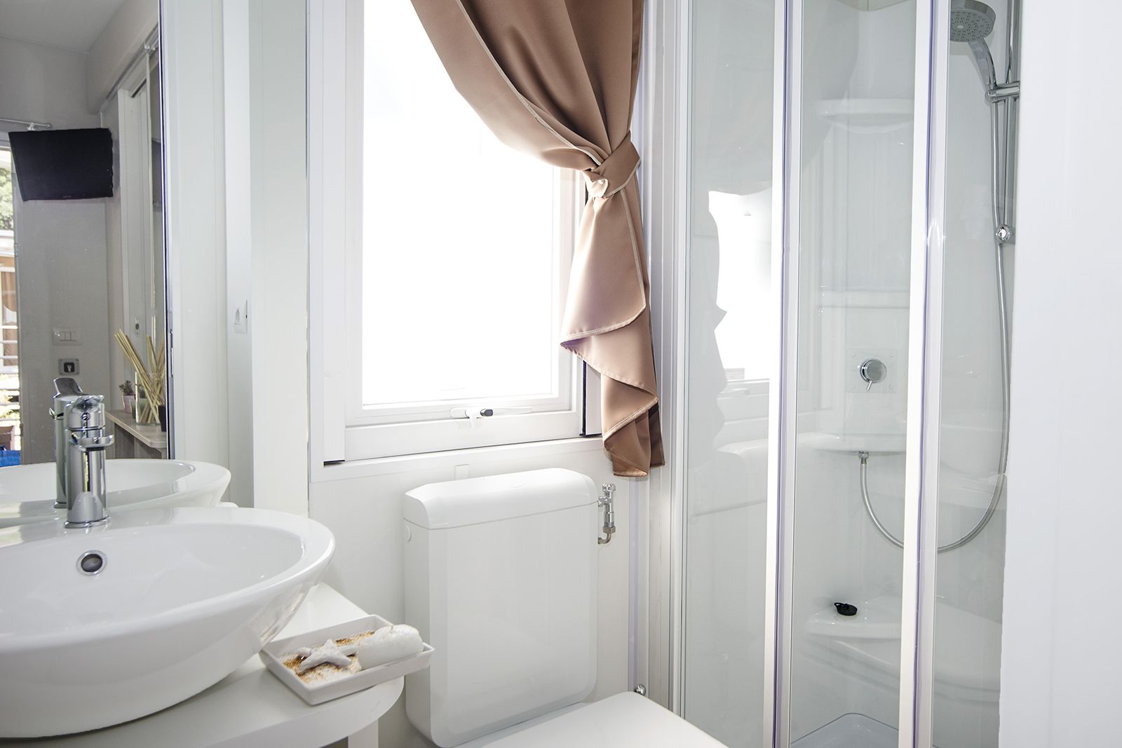 A modern bathroom with a white sink, toilet, and glass shower enclosure.