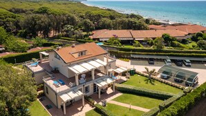 A large villa with multiple terraces, a swimming pool, and a view of the sea.