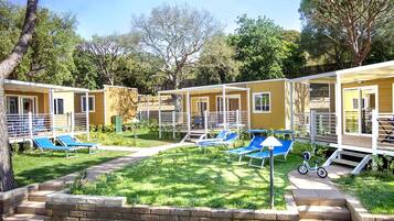A row of single-story cabins with outdoor seating areas and a small garden.