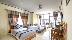 A hotel room with two beds, a wooden table, and a view of the city. - Annecy Hotel Vang Vieng (Vang Vieng)