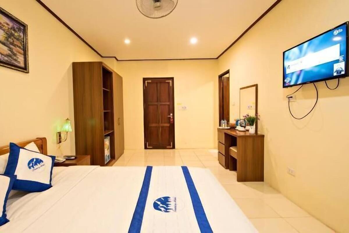 Una camera d'albergo con un letto, una televisione, una scrivania, un armadio e una porta.