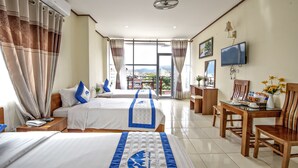 A hotel room with two beds, a TV, a desk with a chair, and a balcony with a view. - Annecy Hotel Vang Vieng (Vang Vieng)