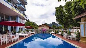 A hotel with a swimming pool, outdoor seating, and a view of mountains. - Annecy Hotel Vang Vieng (Vang Vieng)