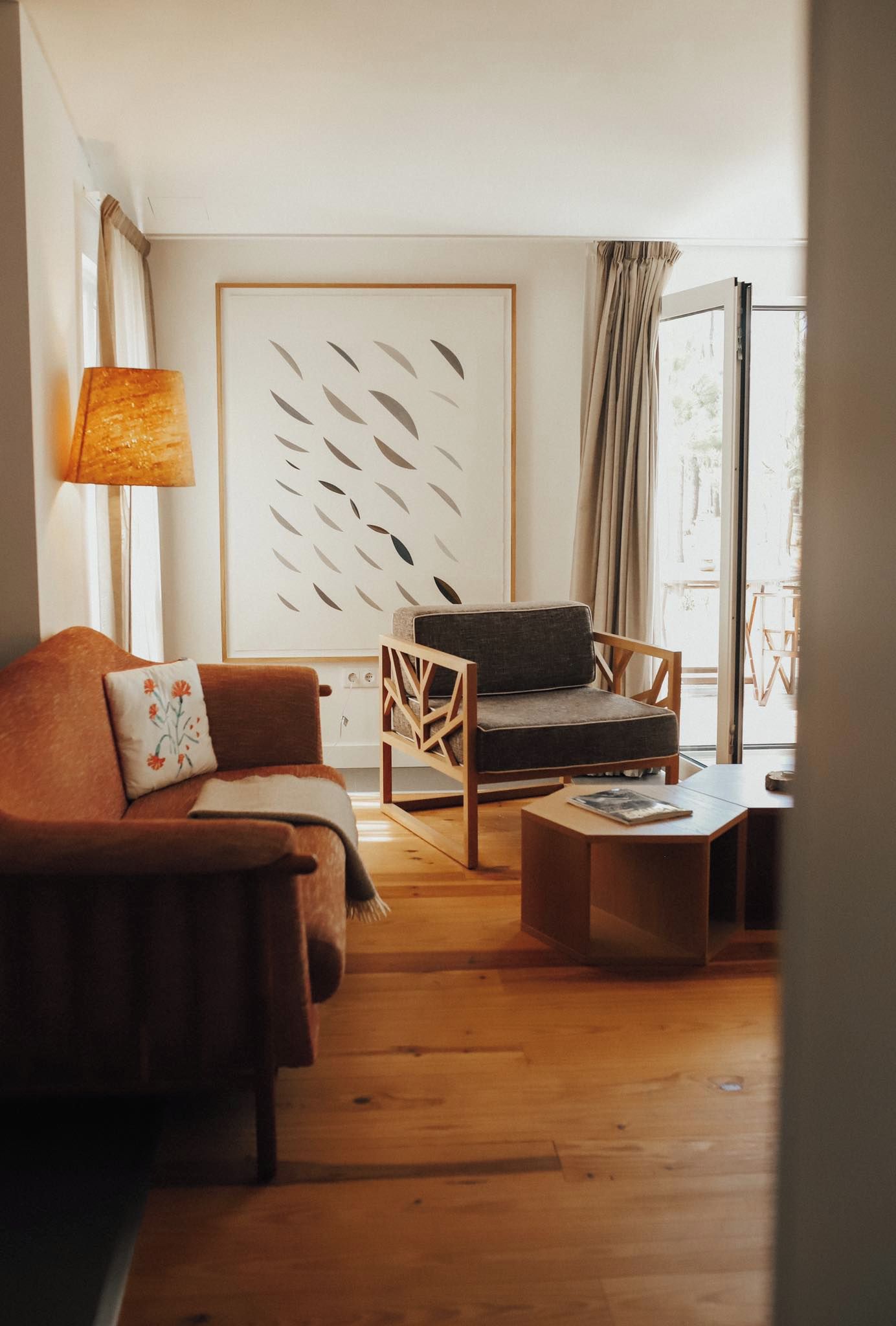 Una sala de estar con sofá, sillón, mesa de centro y una gran obra de arte abstracta en la pared.