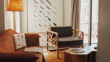 Una sala de estar con sofá, sillón, mesa de centro y una gran obra de arte abstracta en la pared.