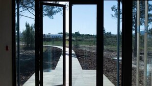 Une pièce dotée de grandes portes vitrées donnant sur un espace extérieur avec une terrasse en bois et une vue dégagée sur les arbres et un bâtiment situé au loin.