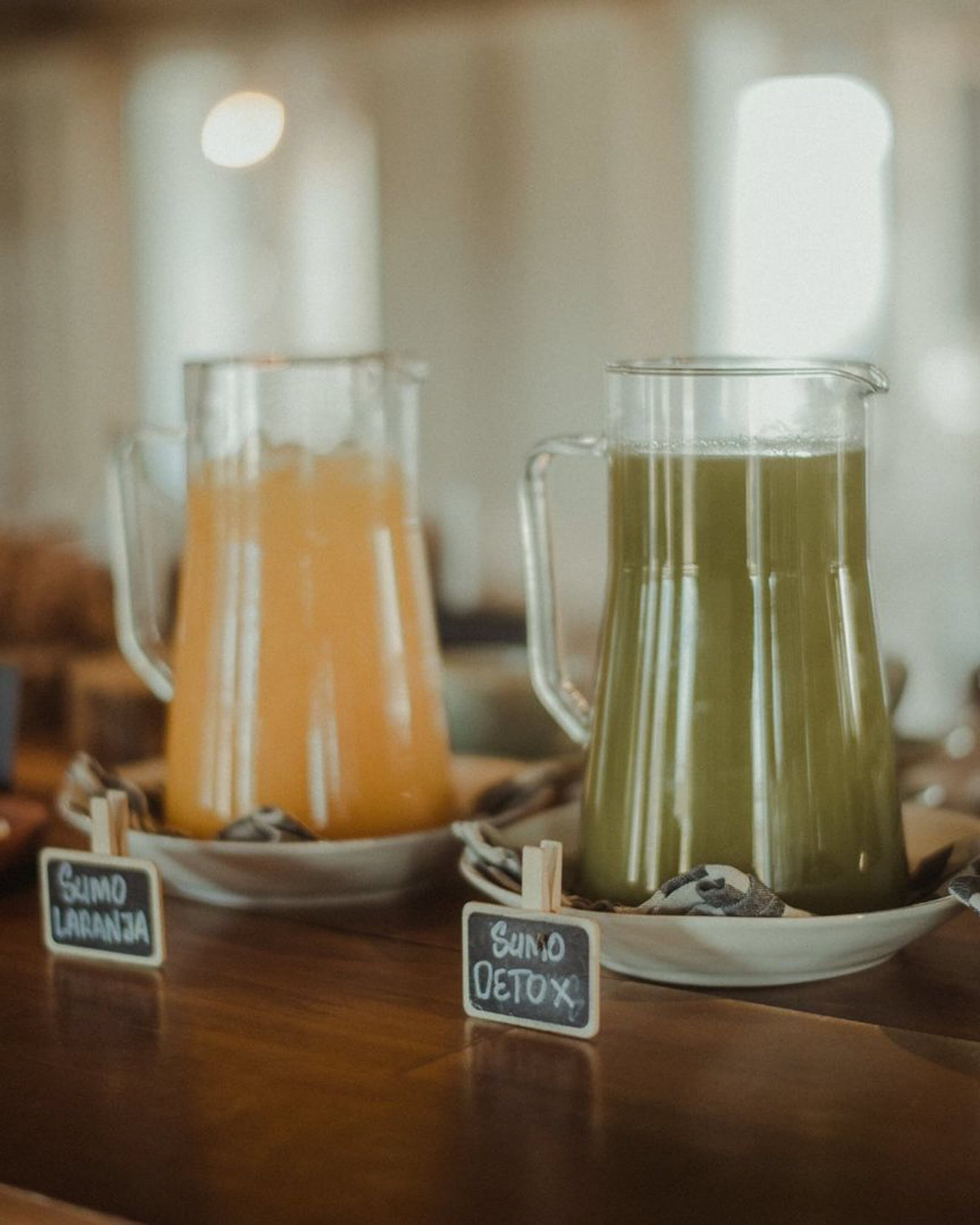 Dos jarras de bebidas con las etiquetas 'Suno Laranja' y 'Suno Detox' sobre una mesa de madera.