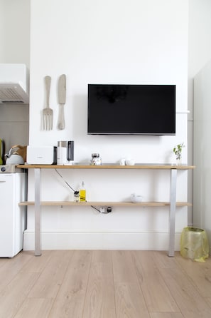 Cozinha moderna com TV embutida, prateleiras de madeira e eletrodoméstico de aço inoxidável.