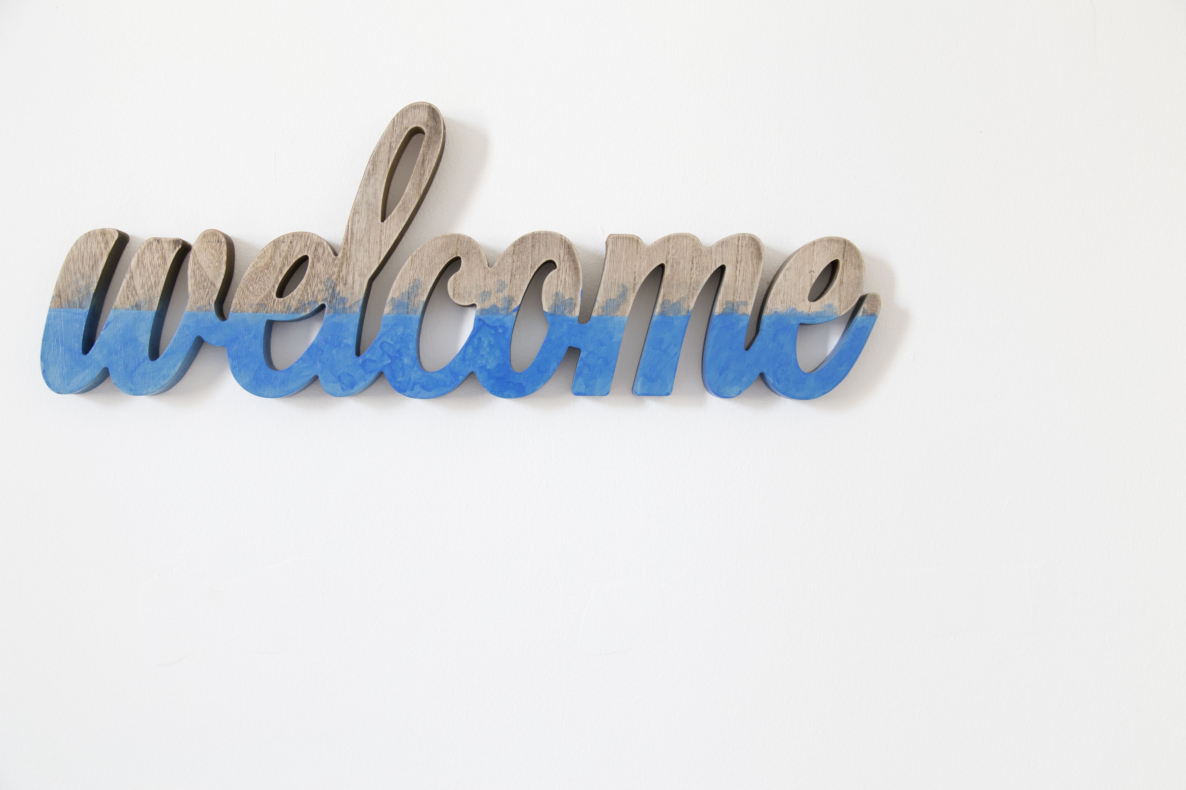 A wooden sign with the word "welcome" in a cursive font.