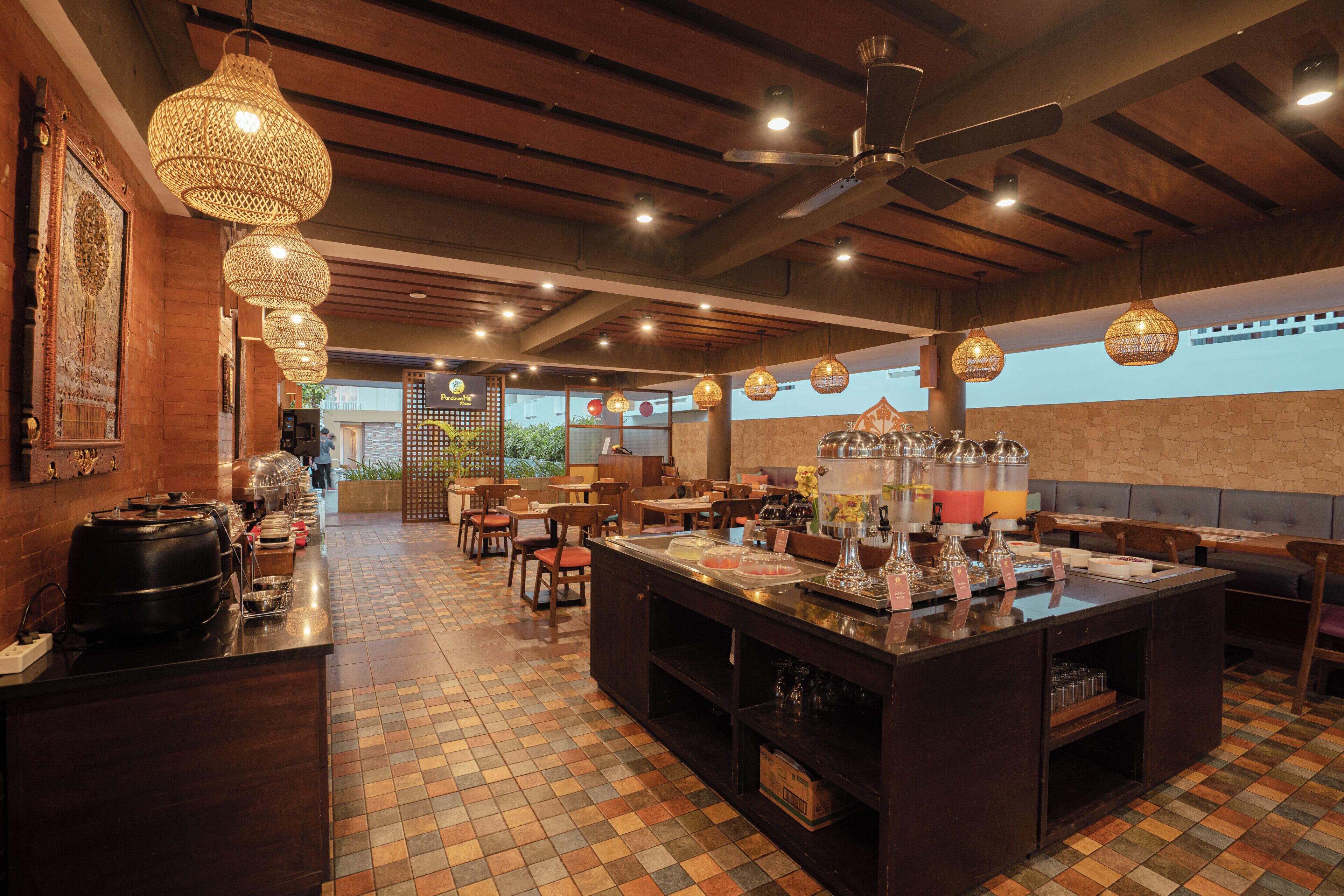 A restaurant with a buffet, wooden ceiling, and hanging lights.