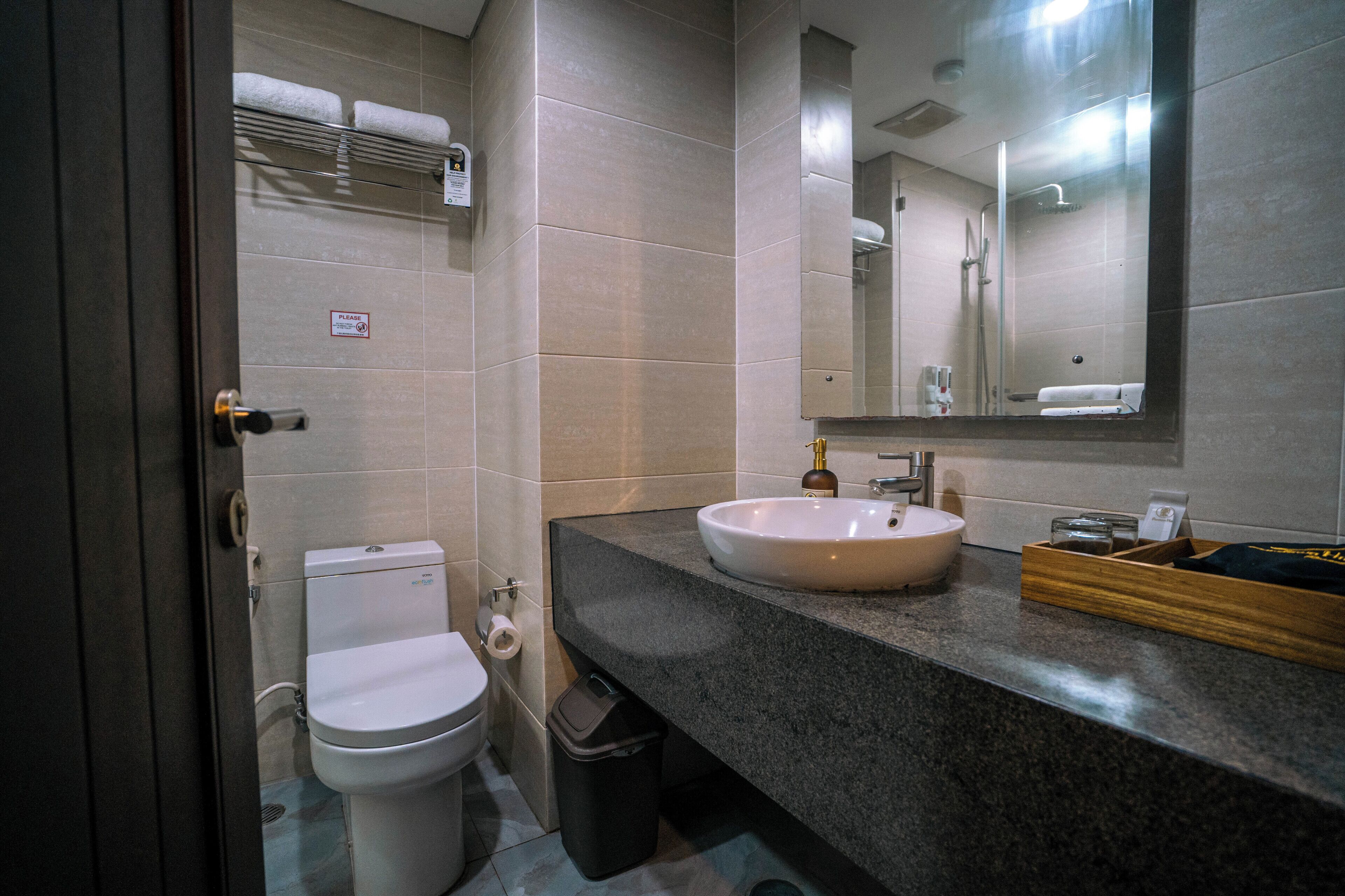 Un baño moderno con inodoro, lavamanos, espejo y perchero para toallas.