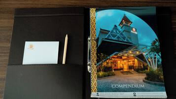 A black leather-bound book with a photograph of a building labeled 'COMPENDIUM' and a business card.