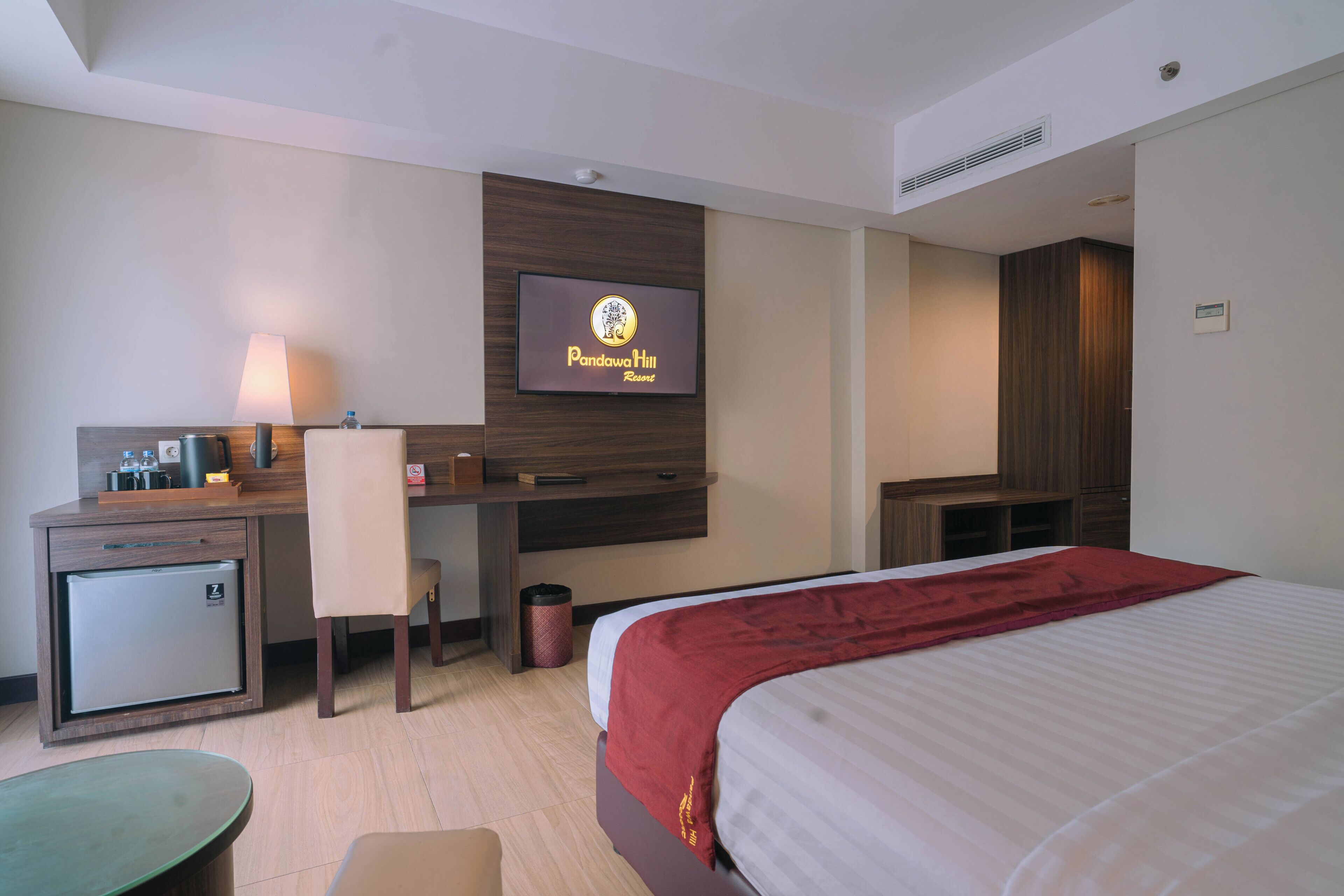 A hotel room with a bed, desk, chair, and a television displaying the hotel name.