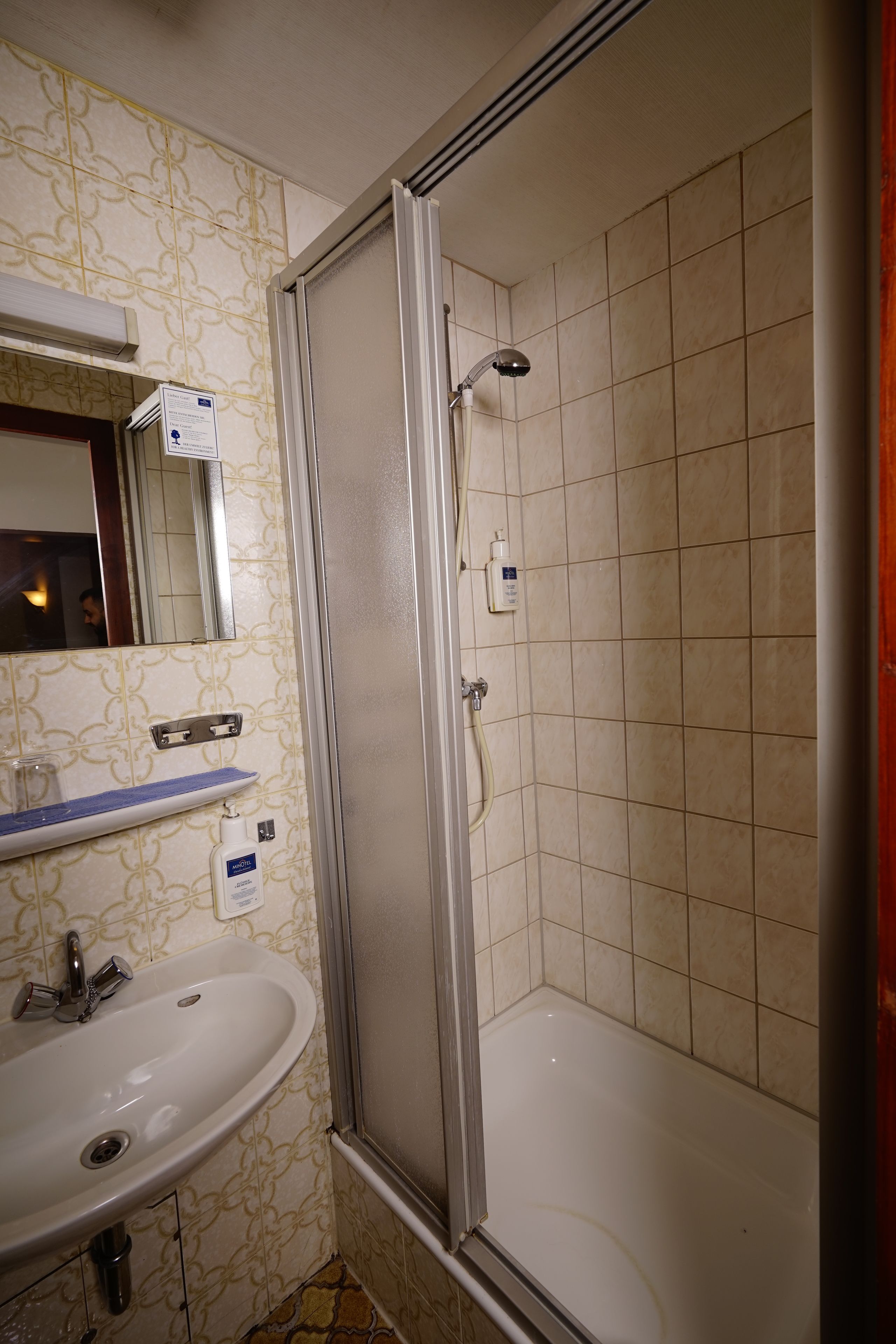 Un baño con lavamanos, espejo y cabina de ducha.