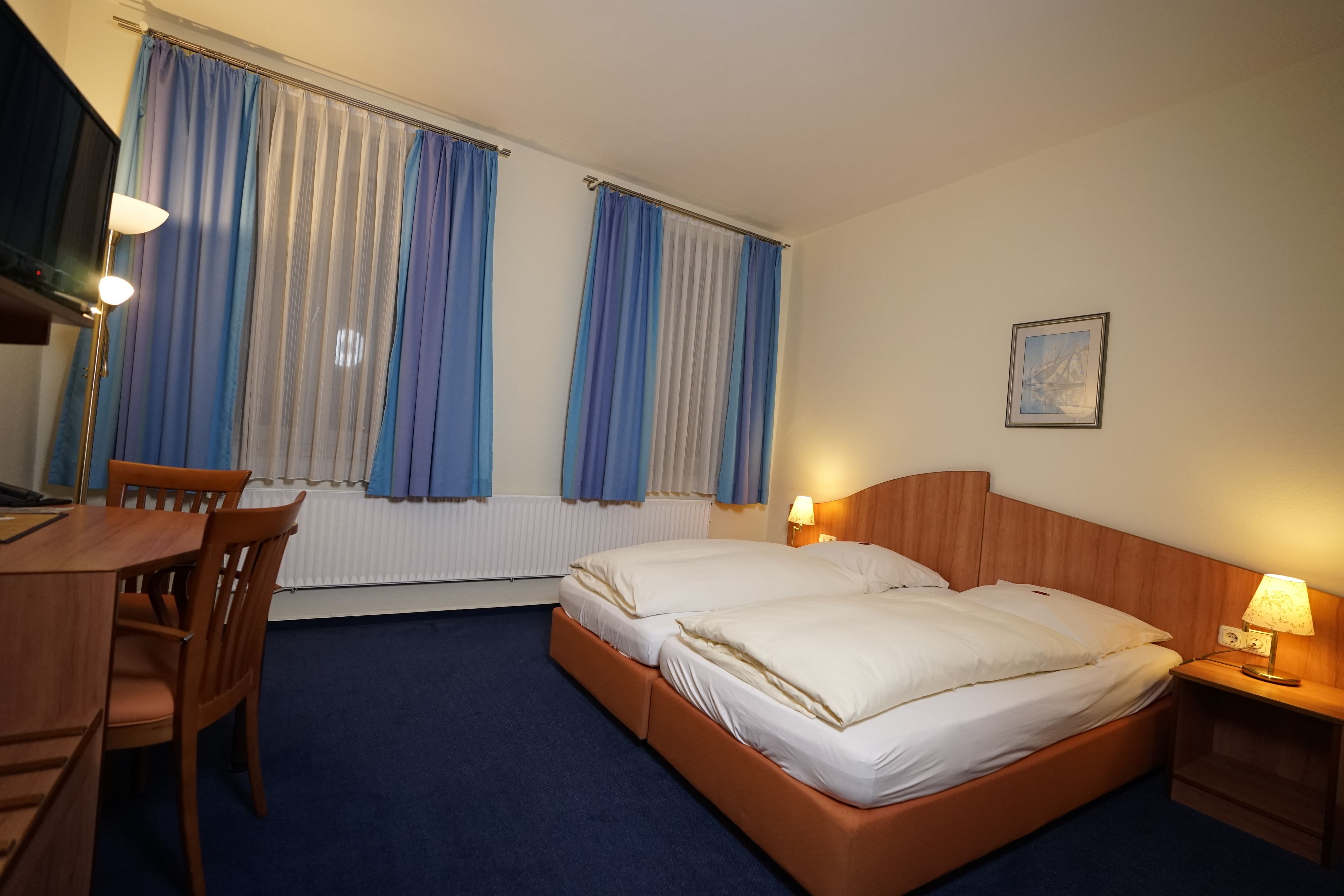 Una habitación de hotel con una cama, un escritorio y una silla.