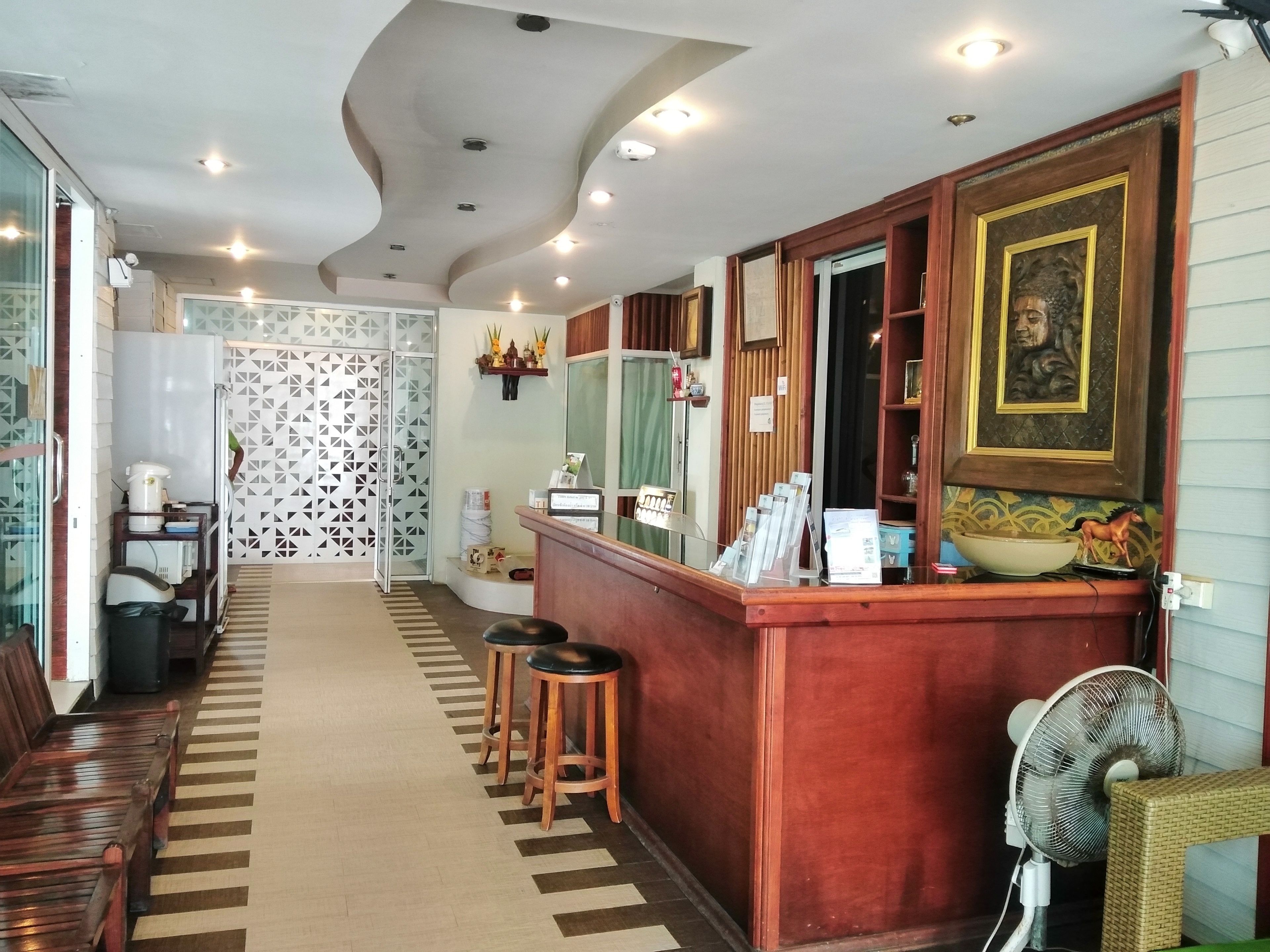 Un espace d’accueil avec un comptoir en bois, un ventilateur et un mur décoré de motifs.