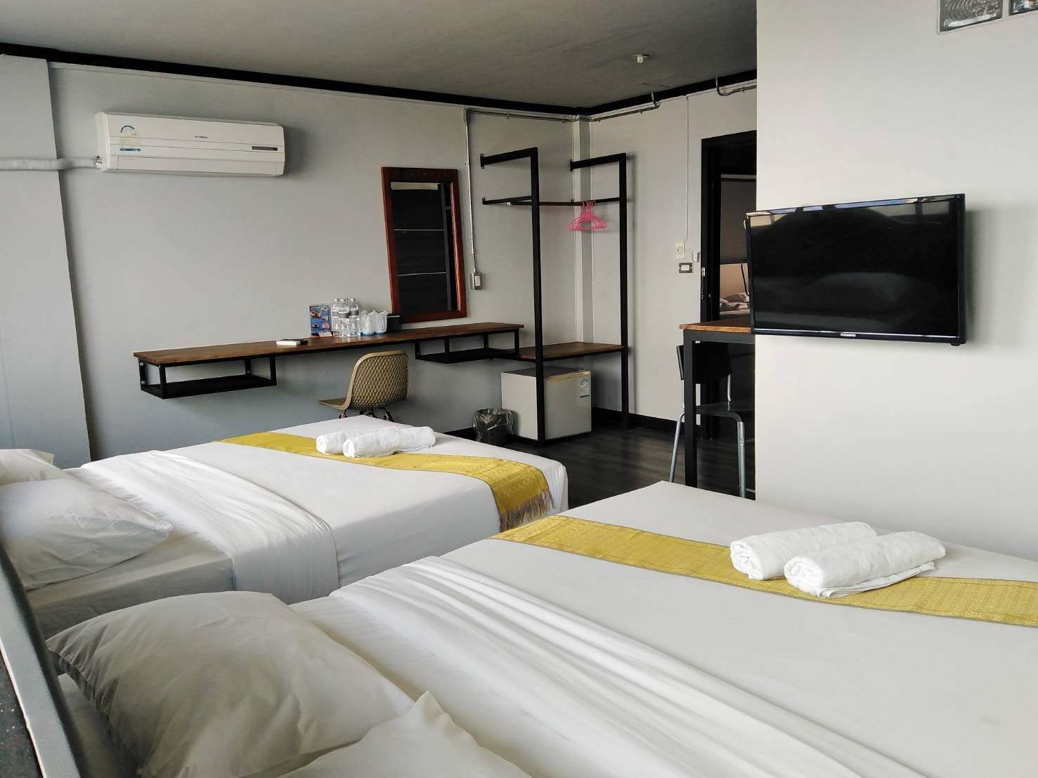 Habitación de hotel con dos camas, un escritorio, una silla, un televisor y un armario.