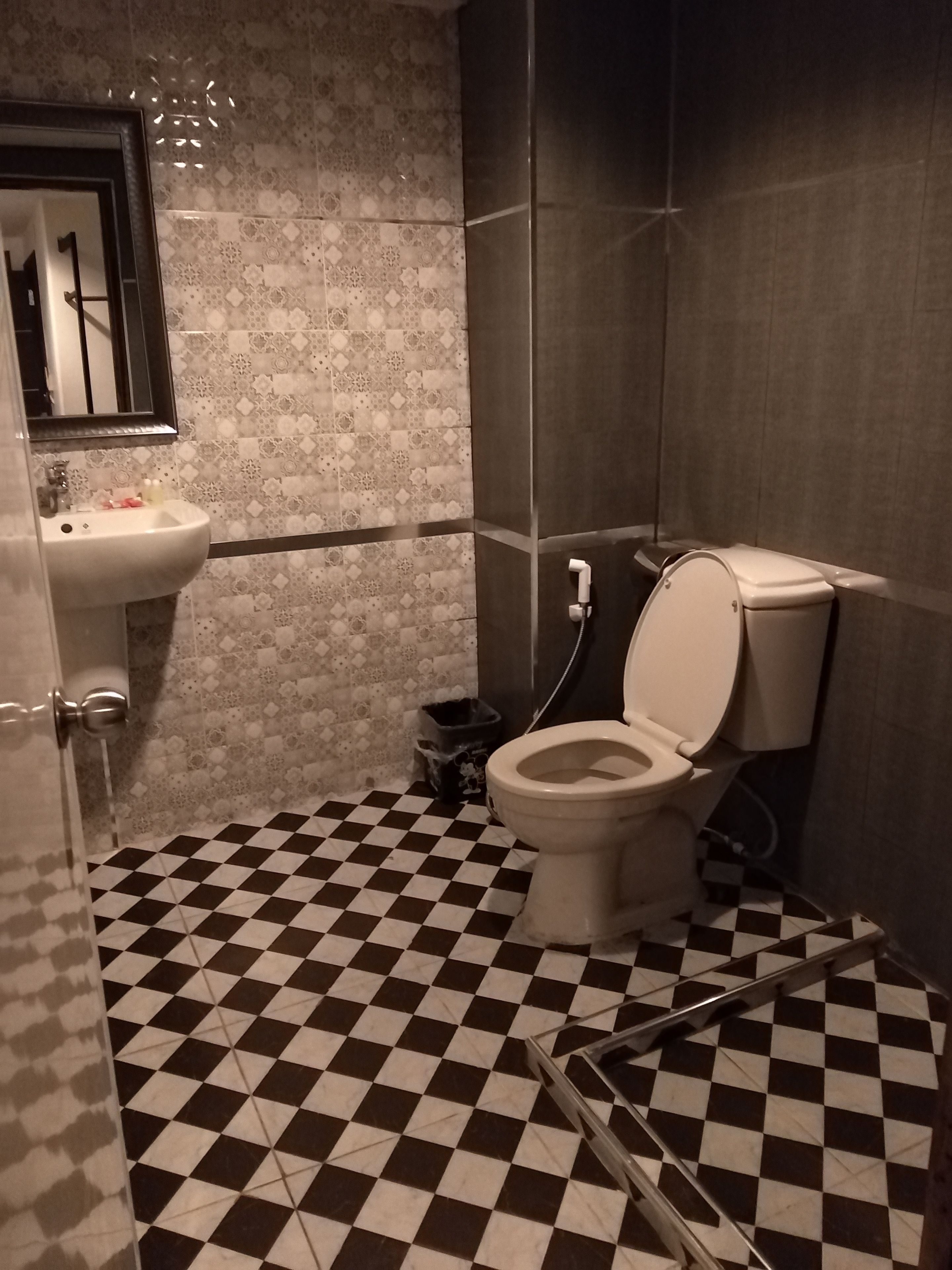 Ein Badezimmer mit Schachbrettboden, Toilette, Waschbecken und Spiegel.